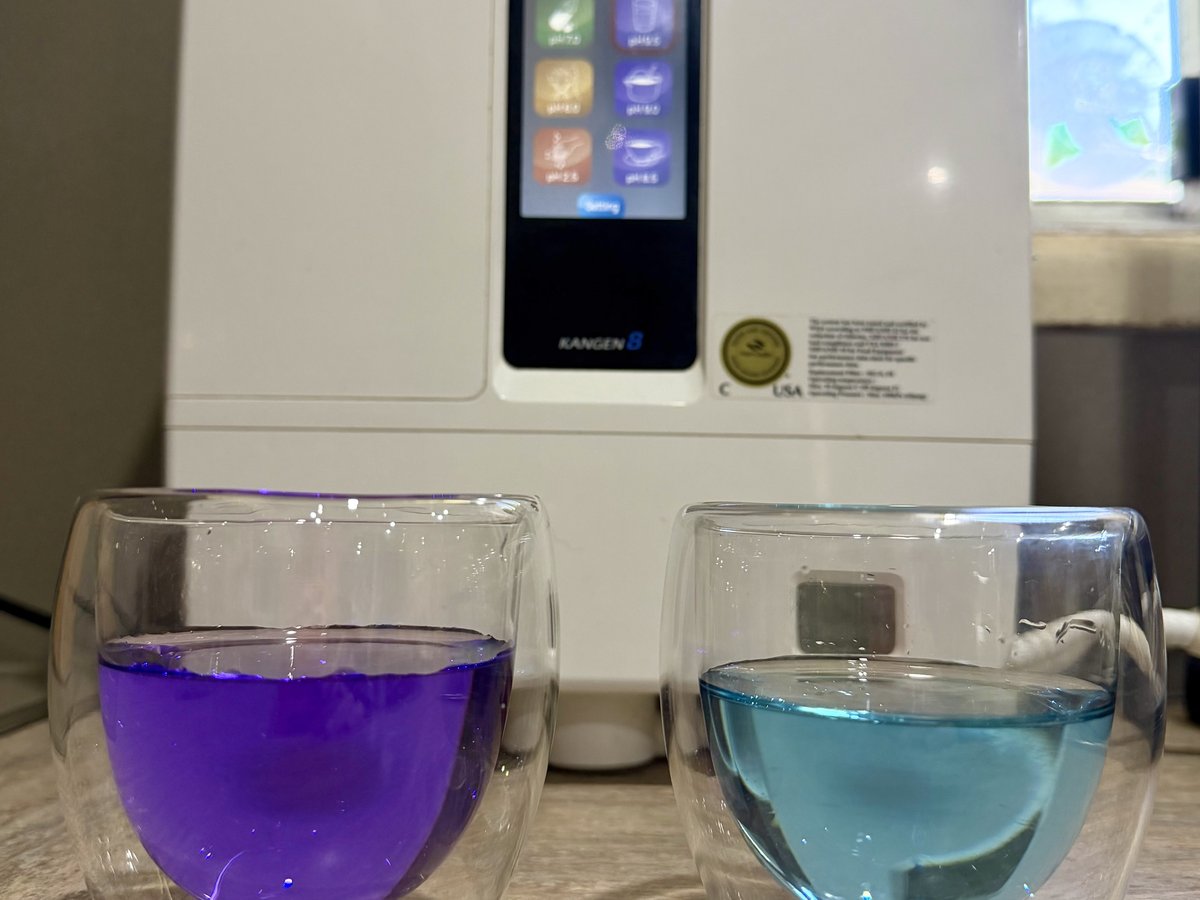 A pH colour test showing deep purple alkaline Kangen water beside neutral tap water, in front of a LeveLuk K8 machine